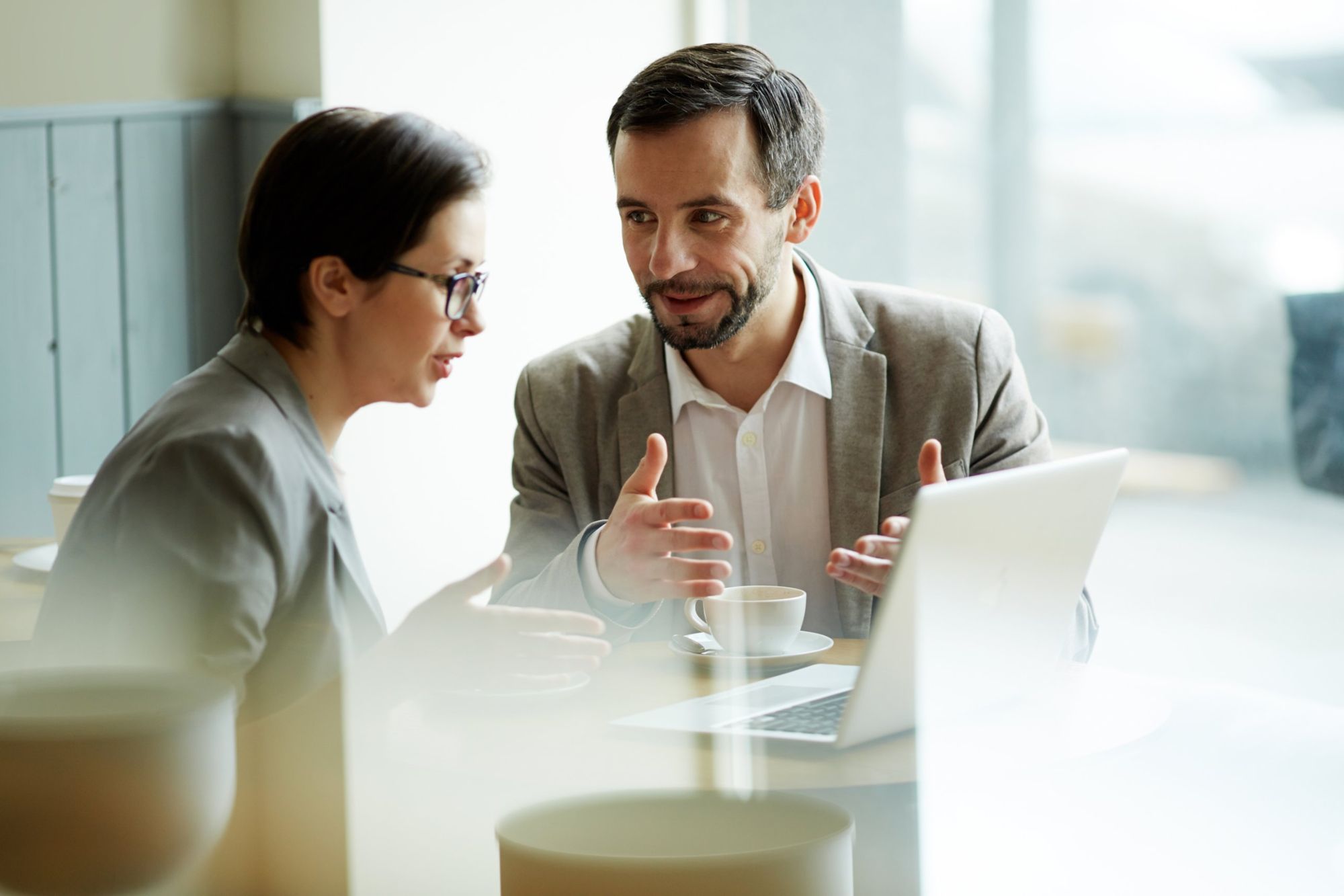 Dos personas conversan frente a un laptop