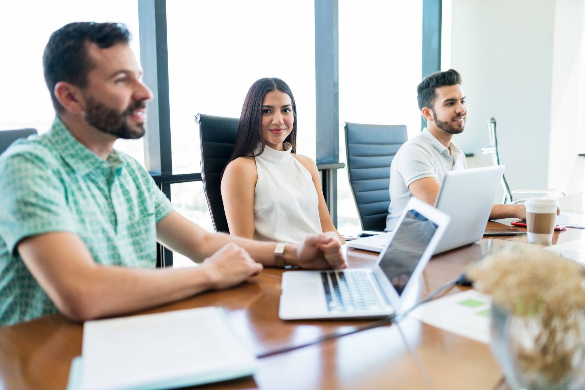 Equipo de profesionales en una sala de reuniones con laptops, junto a un ventanal